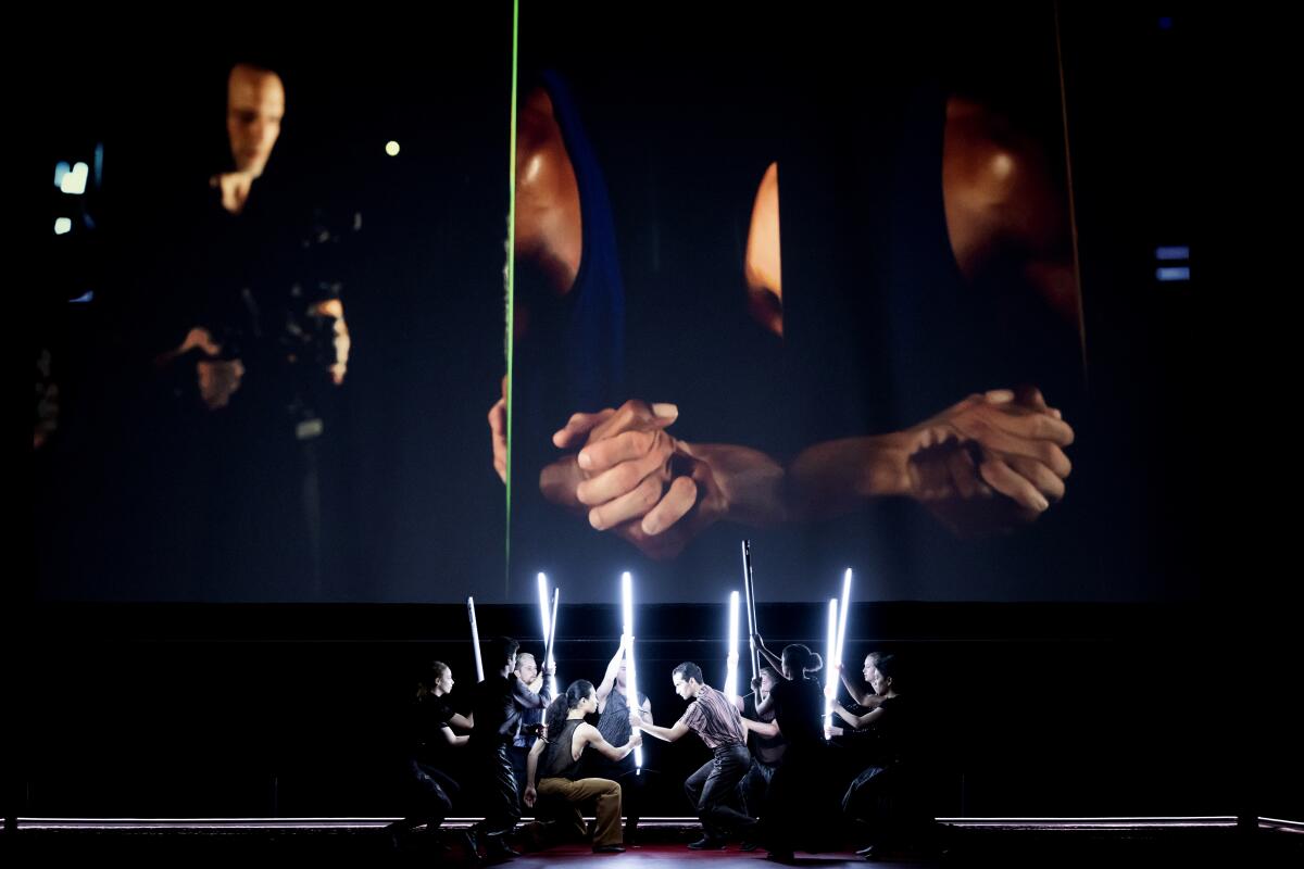 Dancers hold light sticks on stage.