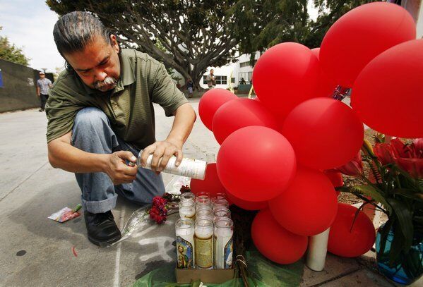 Raphael Torres, son of Santa Monica College shooting victim Margarita Gomez, lights candles at a memorial created at the site his mother was killed.