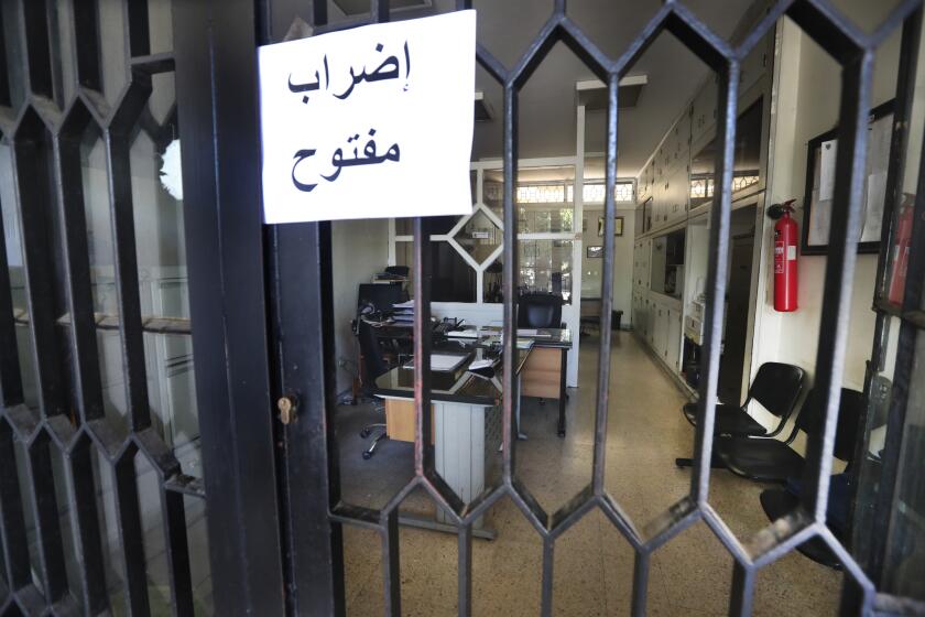 An Arabic placard reads: "Open strike", is posted on a door of an empty municipality office, in Bramiyeh, south Lebanon, July 27, 2022. Tens of thousands of Lebanese public sector workers are on strike for a sixth week as they struggle to cope with the country's crippling economic crisis. (AP Photo/Mohammed Zaatari)