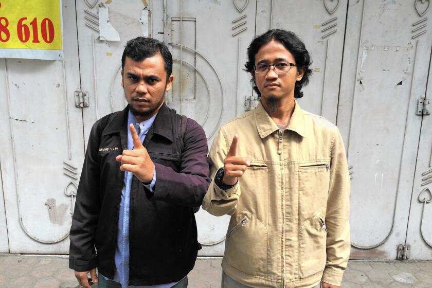 Afrian and Rahmat, both 33, raise their fingers in a salute to Islamic State.