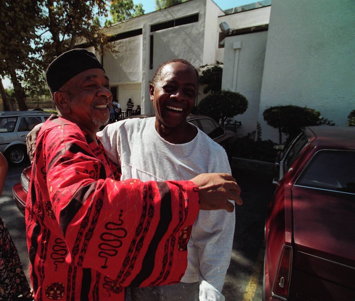 Cecil Fergerson, left, hugs artist Elliott Pinkney outside the Watts Mafundi Institute in 1997, when Pinkney repainted a mural at the site that he'd originally painted years before.