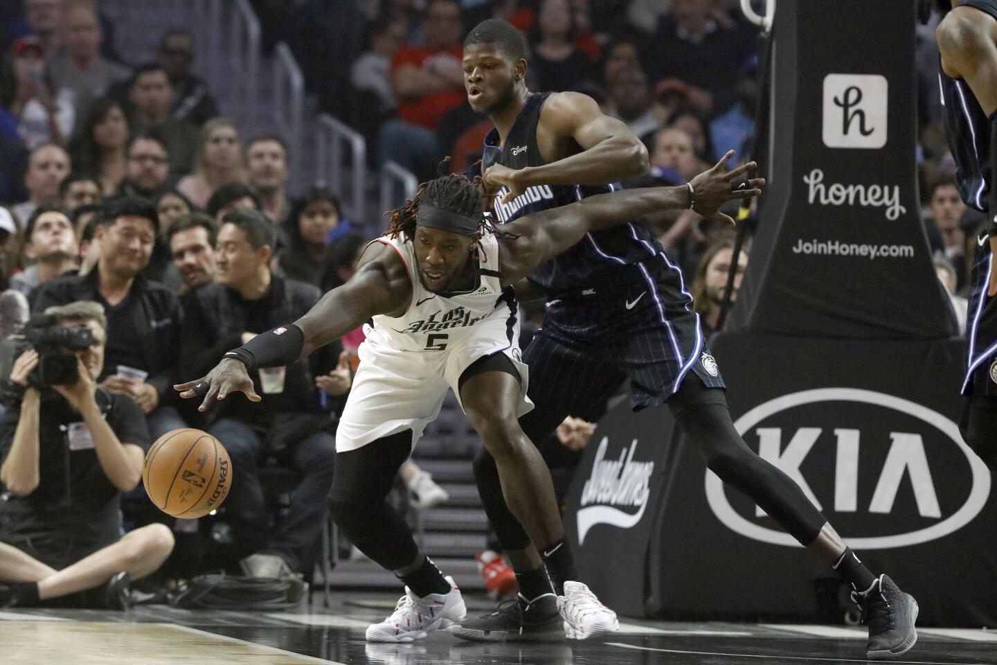 Clippers forward Montrezl Harrell chases a loose ball in front of Magic center Mo Bamba during the first half of a game Jan. 16 at Staples Center.