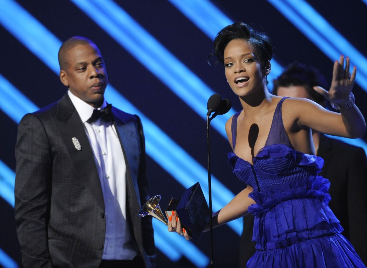 A man in a suit and a woman in a blue dress accept an award onstage