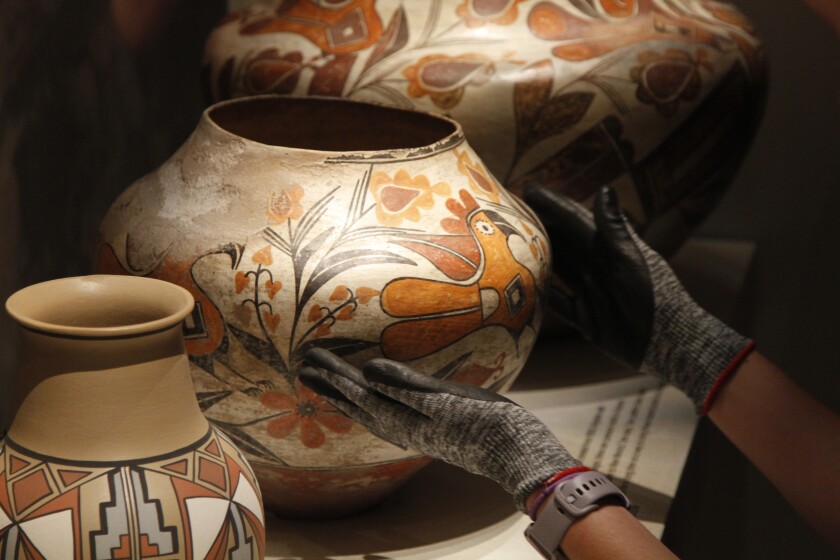Finishing touches are made on a community-curated exhibition of Native American pottery from the Pueblo Indian region of the U.S. Southwest on July 28, 2022, at the Museum of Indian Arts and Culture in Santa Fe, N.M. The exhibit includes poems and reflections to give great voice to Indigenous people. Showings also are scheduled at the Metropolitan Museum of Art in New York and museums in Houston and St. Louis. (AP Photo/Morgan Lee)