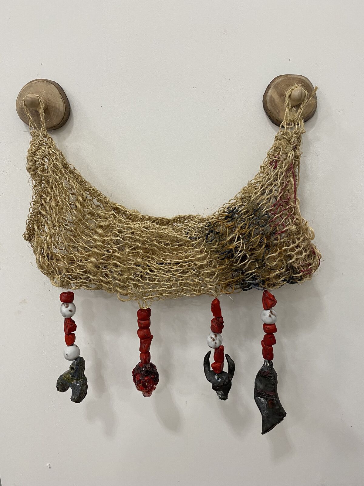 A knitted cradle with charms hanging from it.