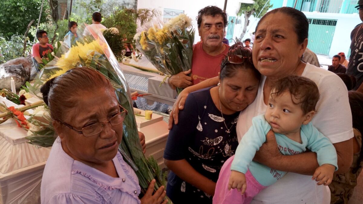 Facunda Villanueva Perez, 67, whose sister was among the 11 killed at the Atzala church in Mexico, holds her grandchild and mourns with relatives at the victims' wake Wednesday.