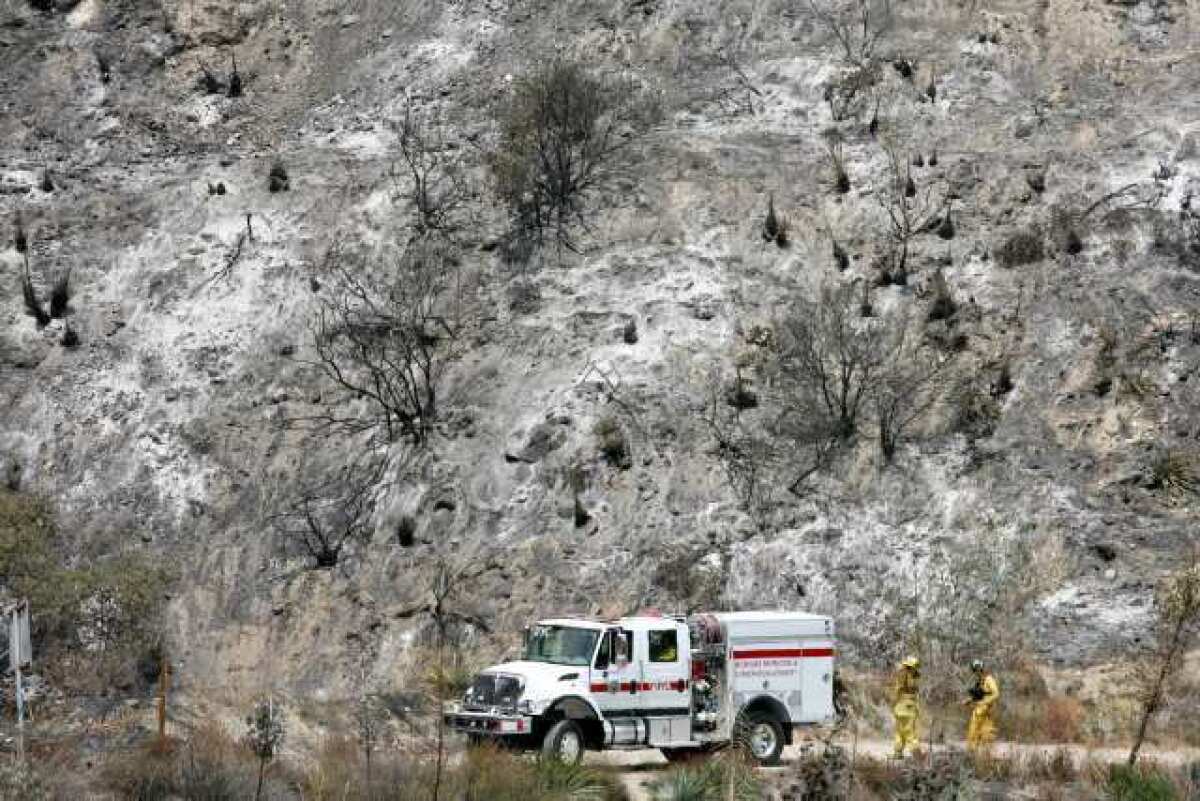 Fire crews work in a barren landscape in Angeles National Forest after the brush fire passed through on Aug. 28, 2009.