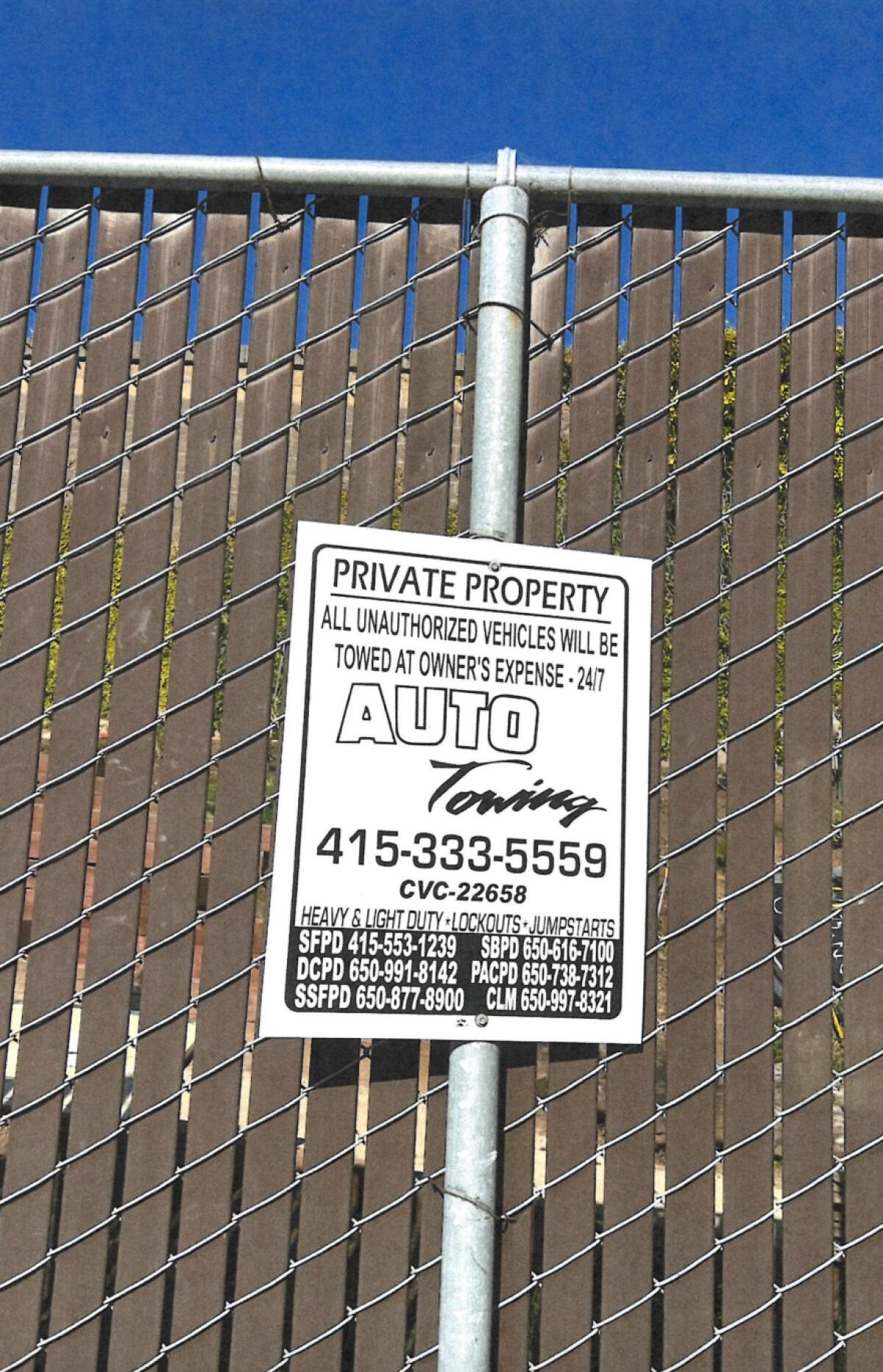 A sign on a fence warning of towing on private property.