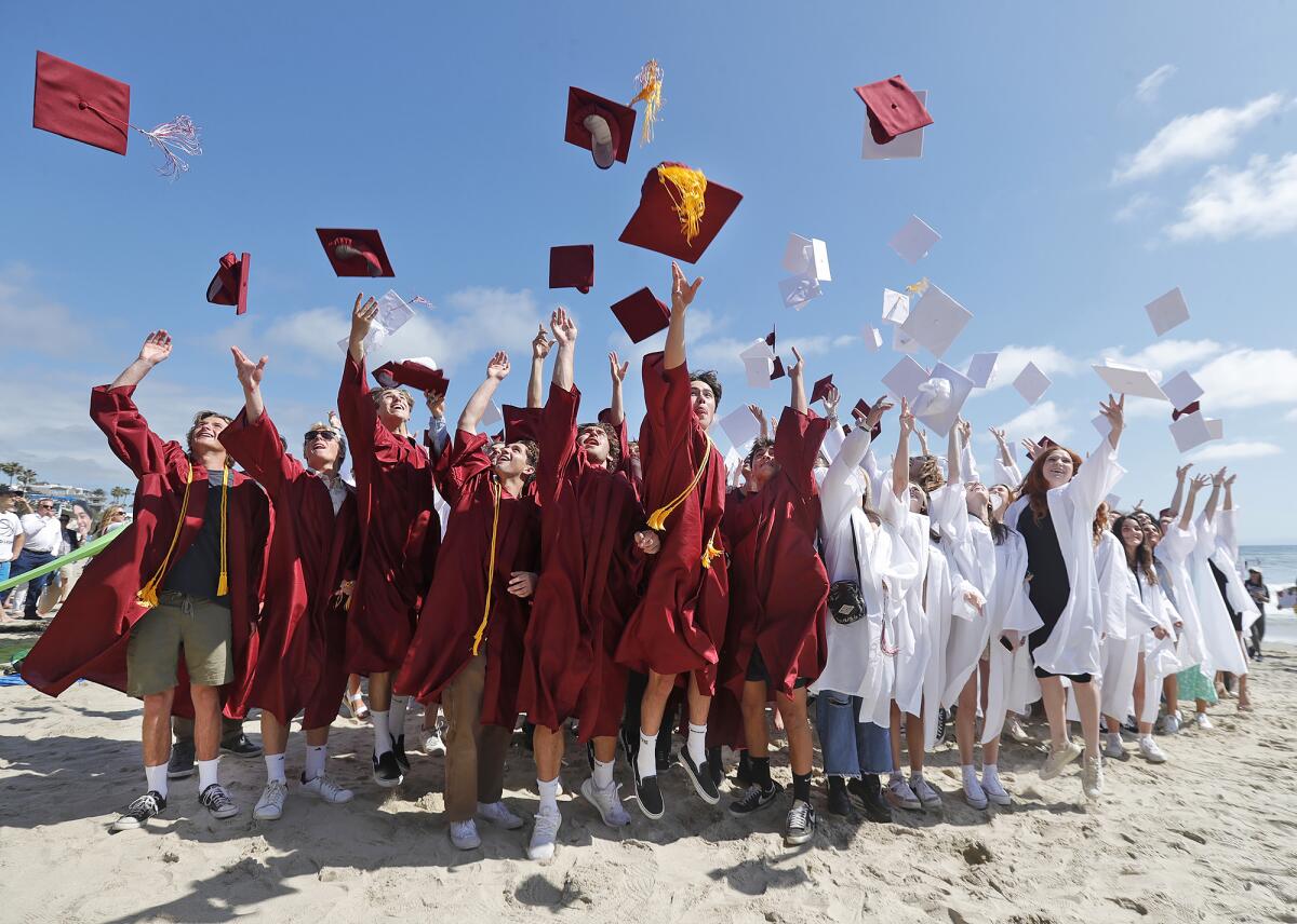 Laguna Beach High seniors throw their caps as they complete the 2023 graduate parade walk down Ocean Avenue to Main Beach.