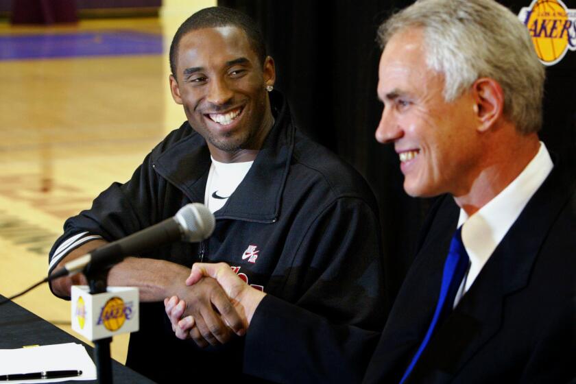 Kobe Bryant shakes hands with Lakers General Manager Mitch Kupchack after the star guard re–signed with the team on July 15, 2004.
