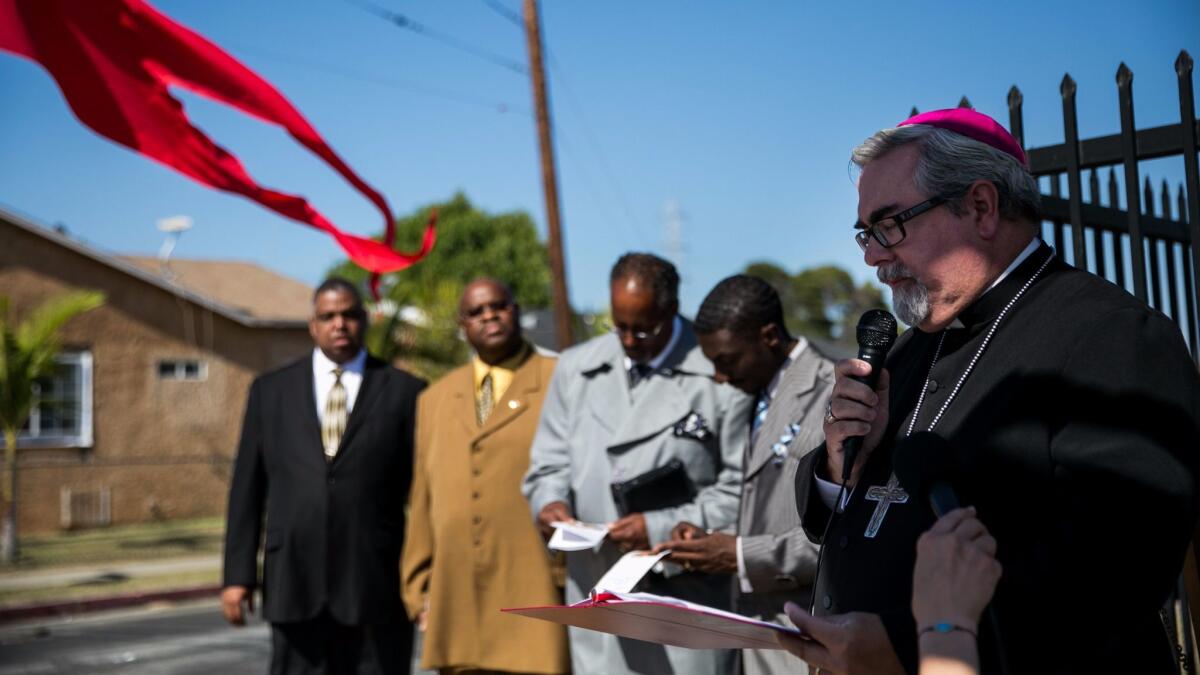 Bishop Guy Erwin, far right, say a prayer in 2015 with the Los Angeles Council of religious leaders as they hold an interfaith prayer service to honor the memory of those who died during the Watts riots.