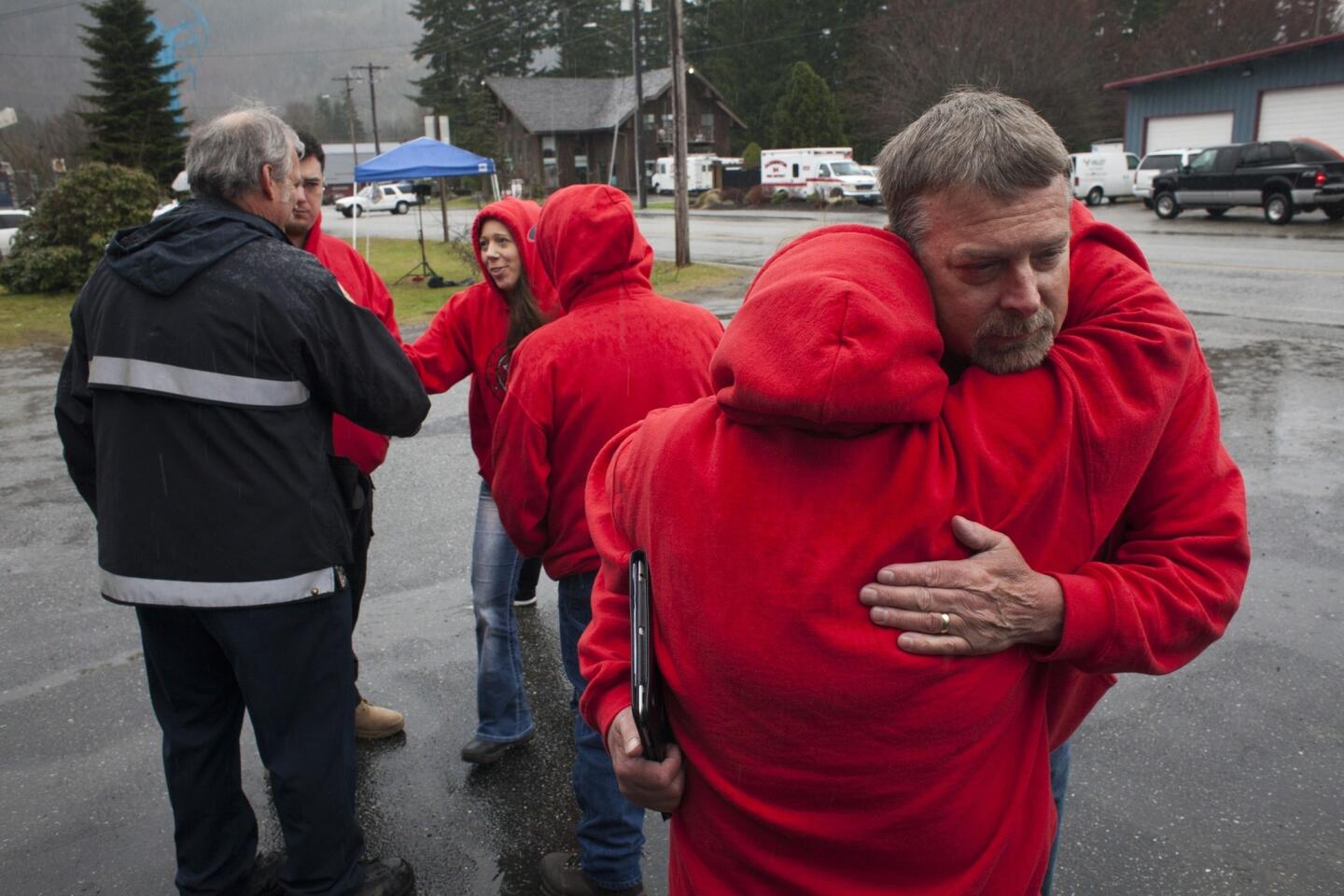 Snoqualmie Indian tribe members Toby Strotz, right, and his sister, Chris Strotz Jacobs, embrace in Darrington, Wash., after the tribe announced a donation of $275,000 for mudslide relief efforts, including for local fire departments, the Red Cross, and others. Fire District 24 Chief Dennis Fenstermaker, left, thanks members of the tribe for the donation.