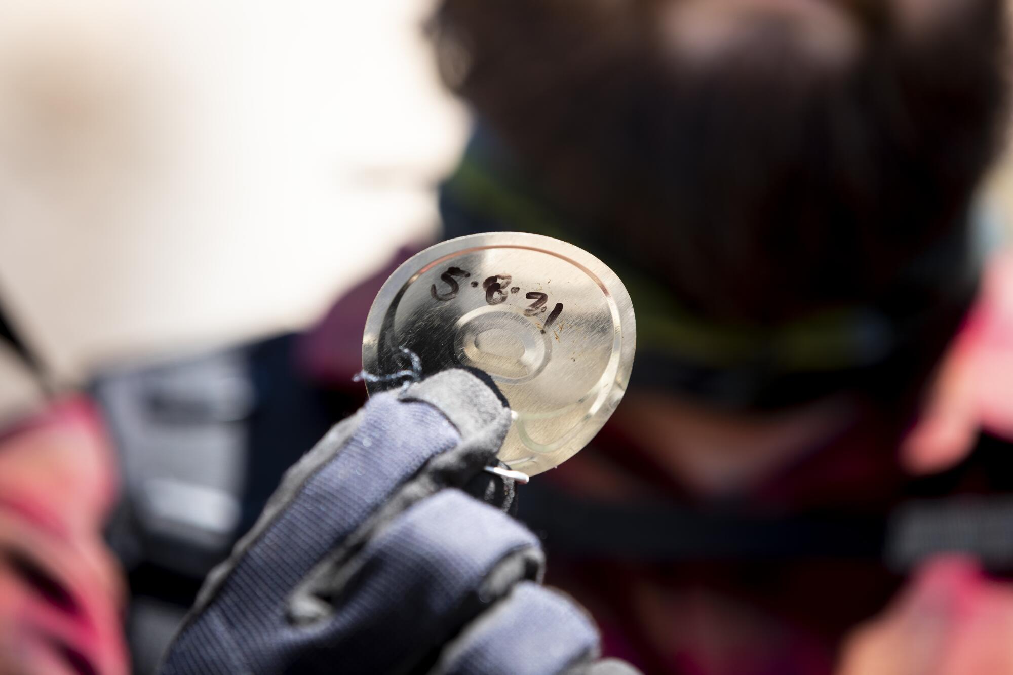 James Cordero holds a lid from a tuna can with a date written on it.