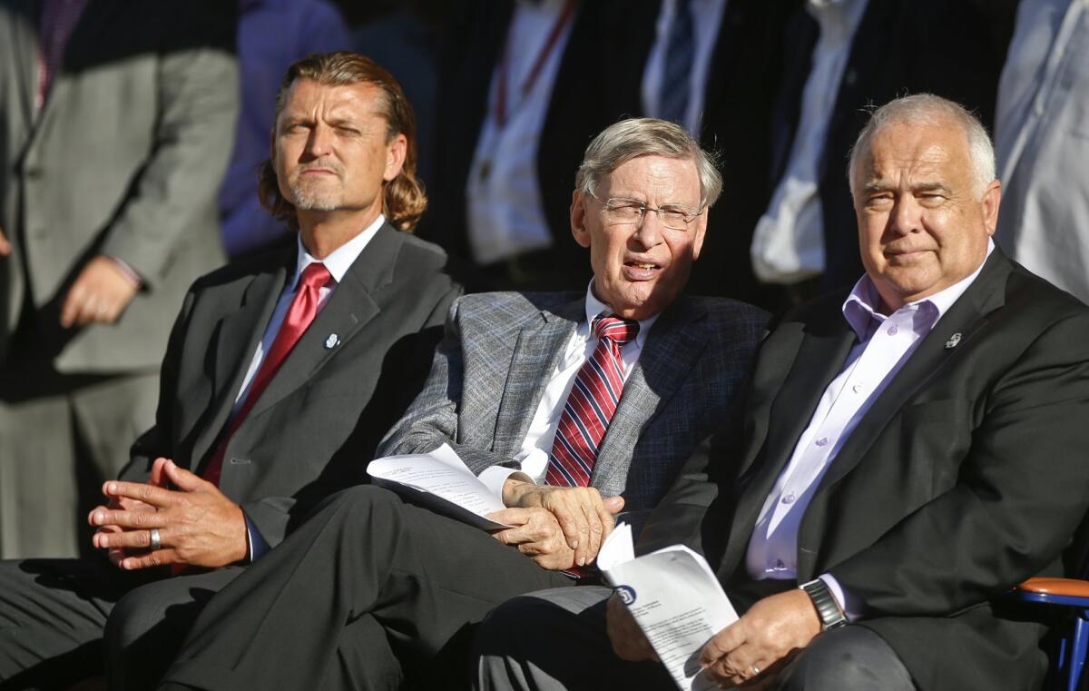 Baseball commissioner Bud Selig, center, sits with San Diego Padres CEO Ron Fowler and former Padres pitcher Trevor Hoffman, left, at a ceremony announcing that part of the Padres' Petco Park is being named Selig Hall of Fame Plaza in honor of the commissioner, who is retiring, Tuesday, Aug. 26, 2014, in San Diego. The ceremony took place prior to a baseball game between the Padres and the Milwaukee Brewers.