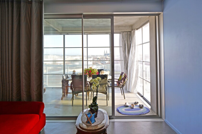 A view from a living room out towards a terrace shows a sunny space lined with transparent corrugated panels