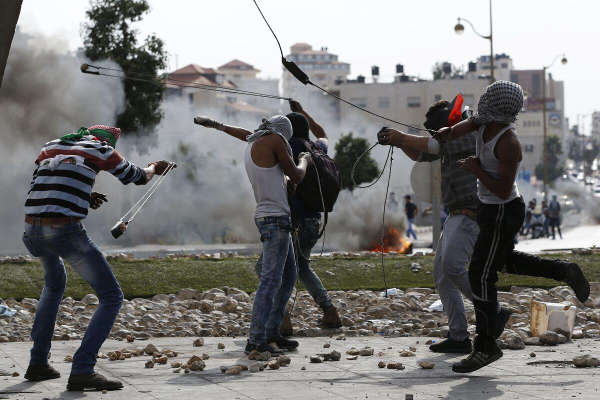 Palestinian protesters use slingshots to launch stones toward Israeli security forces during clashes in Al-Bireh on the northern outskirts of the West Bank city of Ramallah on Tuesday.