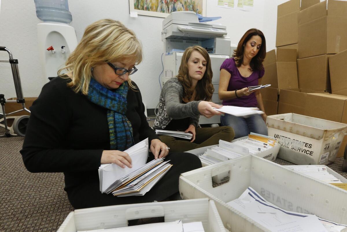 Karen England, executive director of the California Resource Institute, left, and volunteers Grace LeFever and Christina Hill sort through stacks of mail with petitions for a referendum to overturn a California law that allows transgender students to choose which public school restrooms they use in November 2013.