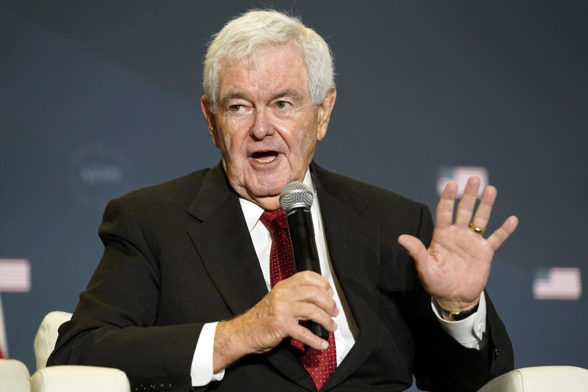 Newt Gingrich, seated, speaks into a hand-held microphone