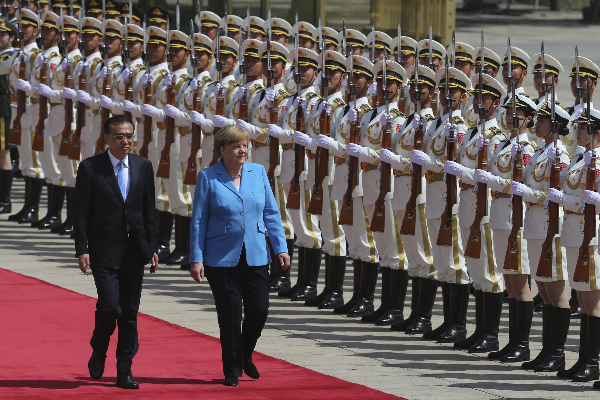 Angela Merkel and Chinese Premier Li Keqiang past the People's Liberation Army honor guards 