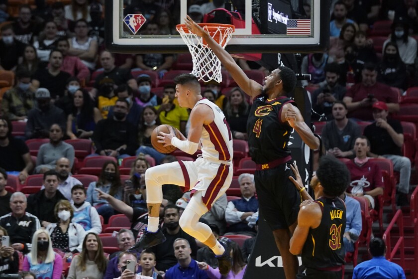 Miami Heat guard Tyler Herro, right, leaps up to pass the ball after he is blocked from a shot by Cleveland Cavaliers forward Evan Mobley (4) and center Jarrett Allen (31) during the first half of an NBA basketball game, Wednesday, Dec. 1, 2021, in Miami. (AP Photo/Wilfredo Lee)