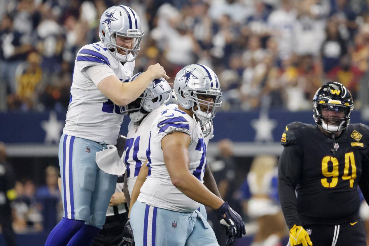 Dallas Cowboys quarterback Cooper Rush (10) celebrates throwing a touchdown pass with offensive tackle Jason Peters (71) and offensive tackle Terence Steele, center, as Washington Commanders defensive tackle Daron Payne (94) looks on in the second half of a NFL football game in Arlington, Texas, Sunday, Oct. 2, 2022. (AP Photo/Ron Jenkins)