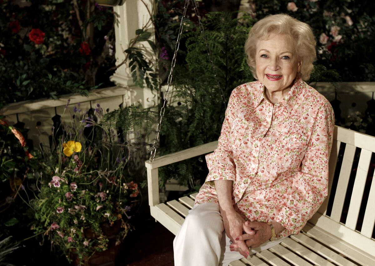 Betty White sits in a porch swing and smiles.