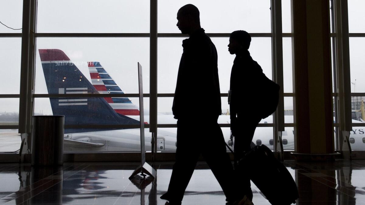Passengers walk through a terminal at Reagan National Airport in Arlington, Va. The Global Business Travel Assn. predicts spending on business travel will surge this year, but it could slow down next year because of rising interest rates and trade wars.