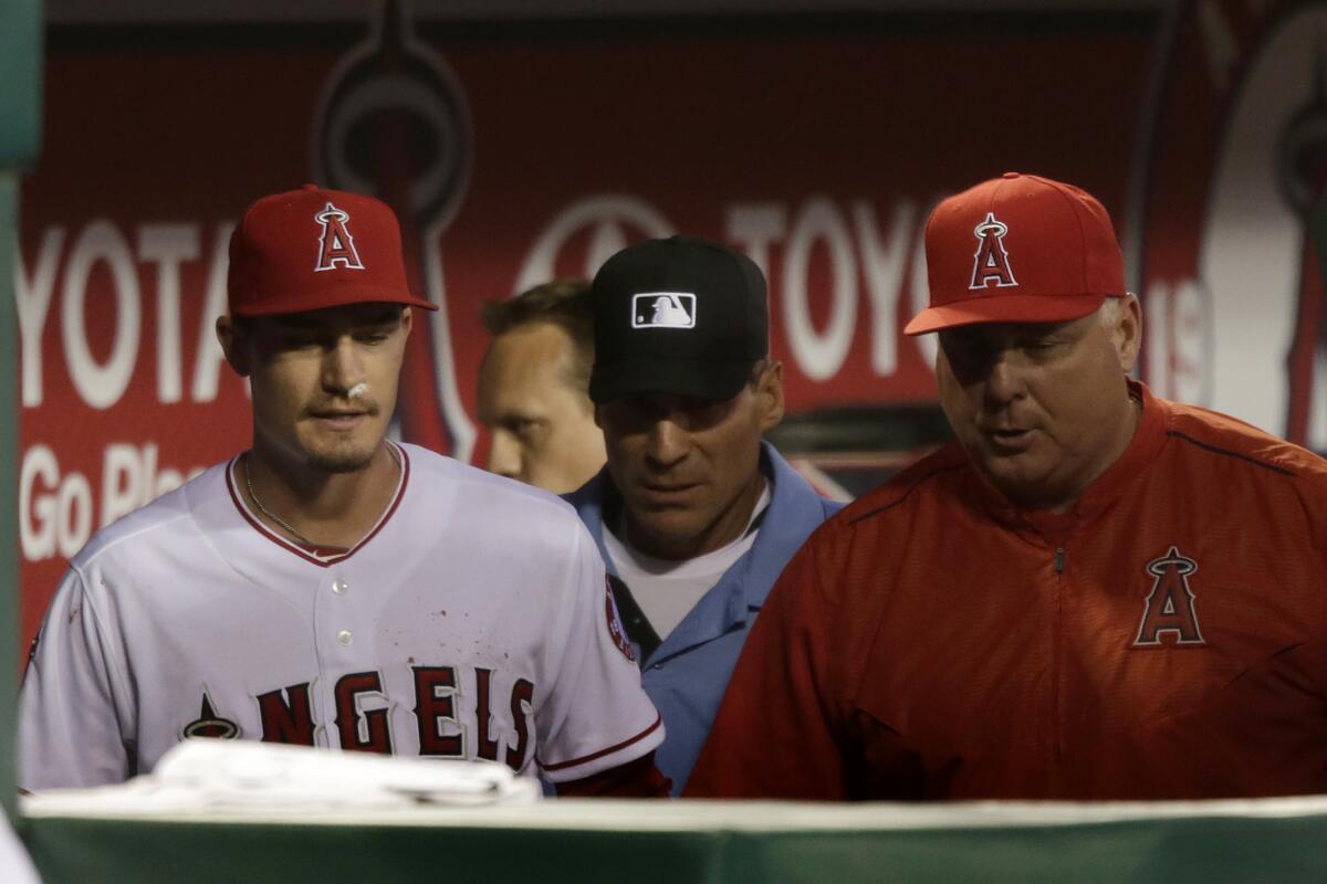 Angels pitcher Andrew Heaney, left, prepares to go back on the field after a brief talk with umpire Angel Hernandez and Manager Mike Scioscia. Heaney suffered a nosebleed while pitching against the Chicago Cubs in April.