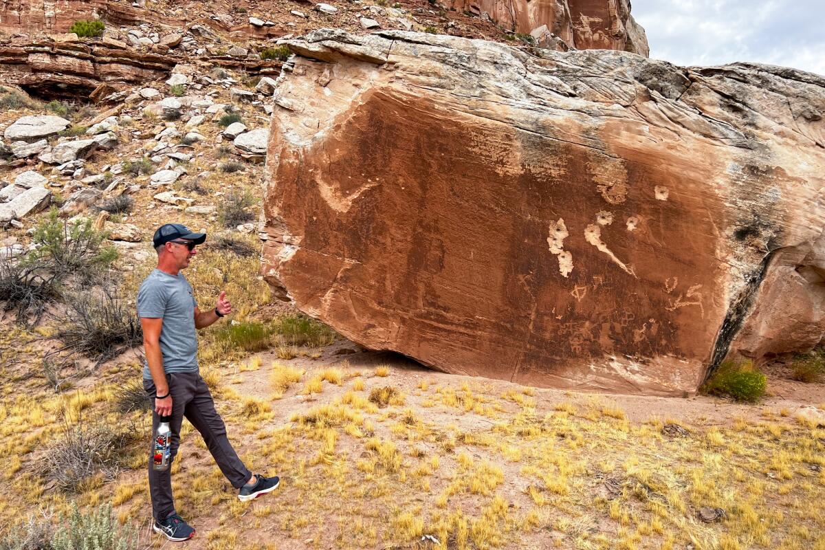 Dave Herrero, showing where someone used a boulder with petroglyphs on it for target practice with a rifle.