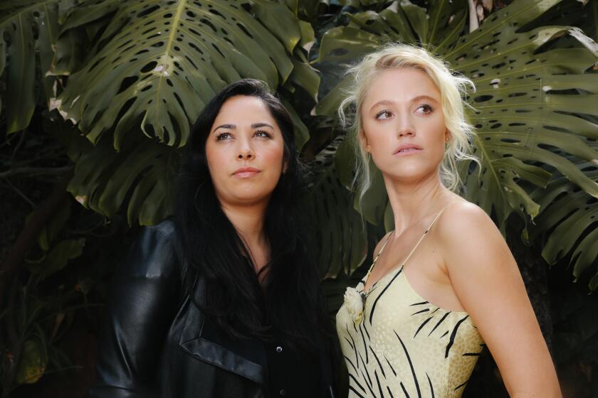 Los Angeles, CA - May 27: Director Chloe Okuna, left, stands with lead actor Maika Monroe, right, for the horror-thriller "Watcher" for a portrait at at her home on Friday, May 27, 2022 in Los Angeles, CA. (Dania Maxwell / Los Angeles Times)