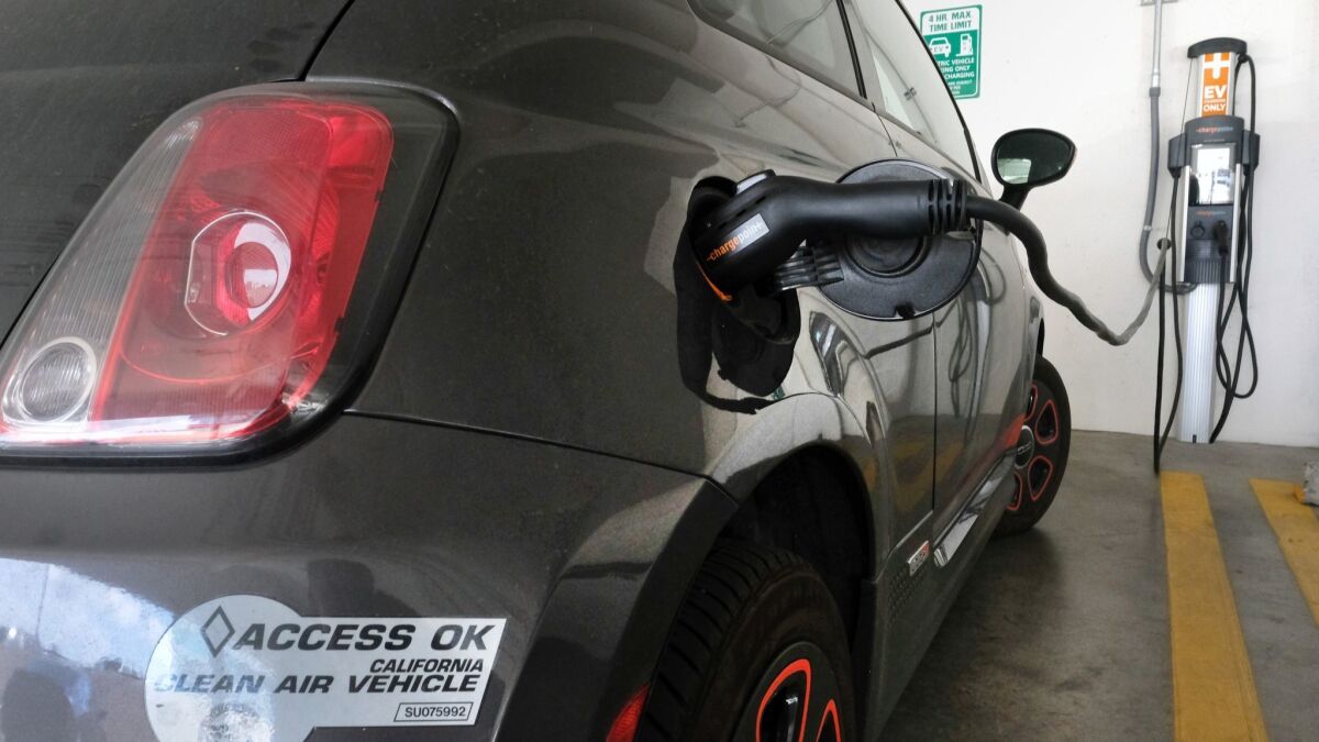An electric Fiat is seen plugged into a charging station in a parking lot in Los Angeles.