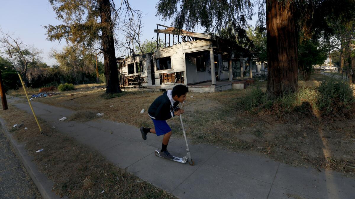 A boy races past a burned-out, abandoned home near North Crescent and Ninth Street.
