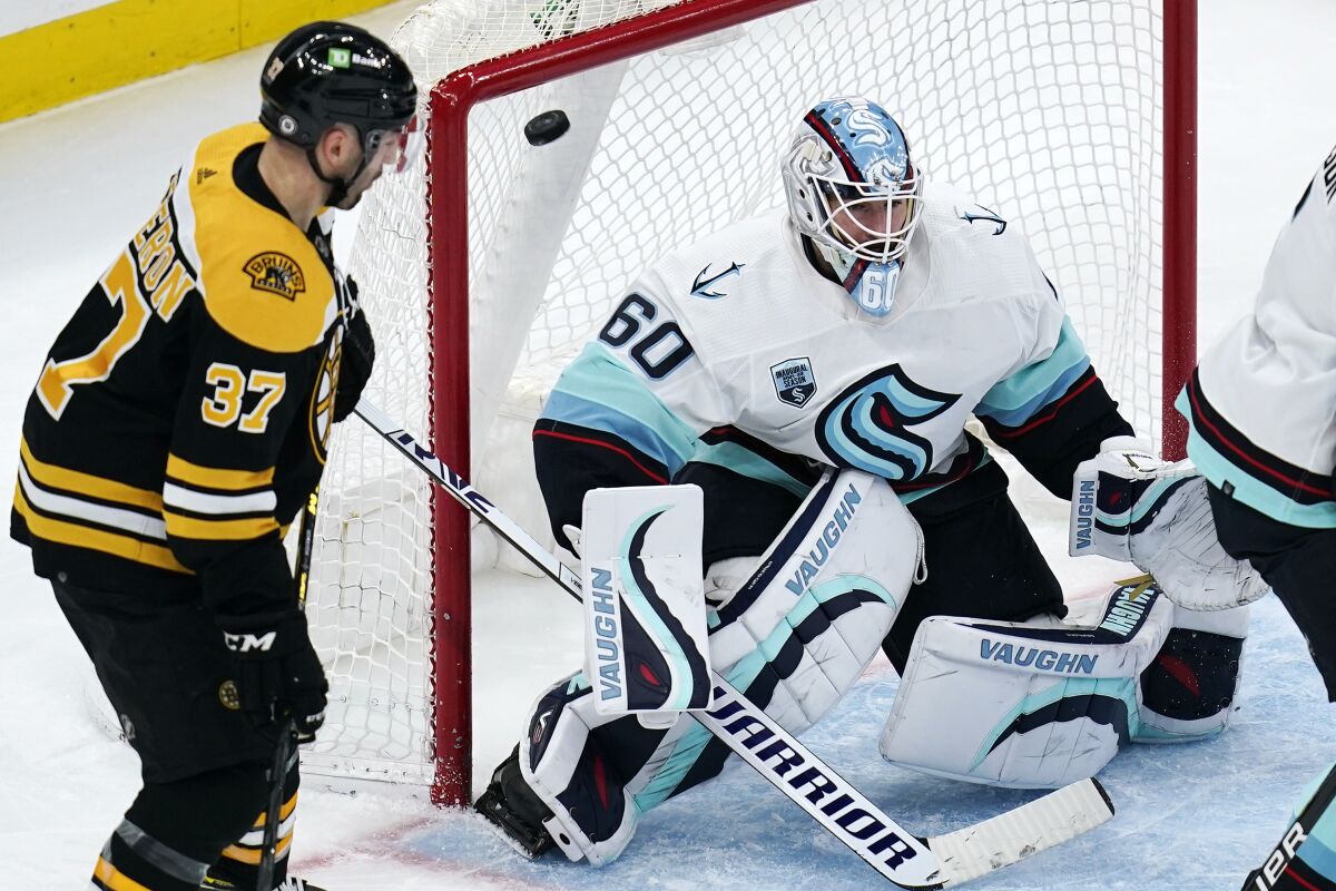 Seattle Kraken goaltender Chris Driedger (60) looks for the shot as the puck sails over his shoulder for a goal by Boston Bruins right wing David Pastrnak during the second period of an NHL hockey game, Tuesday, Feb. 1, 2022, in Boston. At left is Boston Bruins center Patrice Bergeron (37). (AP Photo/Charles Krupa)