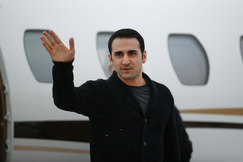 FILE - In this Jan. 21, 2016, file photo, Amir Hekmati waves after arriving on a private flight at Bishop International Airport in Flint, Mich. A former U.S. Marine freed from Iranian custody five years ago is in court with the American government over whether he can collect a multimillion-dollar payment from a special fund for victims of international terrorism. Newly filed court documents show that the FBI opened an investigation into Hekmati, on suspicions that he went to Iran to sell classified information to the regime. He vigorously disputes those allegations. (AP Photo/Paul Sancya, File)