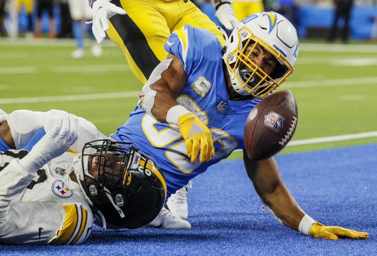 Chargers running back Austin Ekeler spikes the ball next to Pittsburgh Steelers defensive end Taco Charlton.