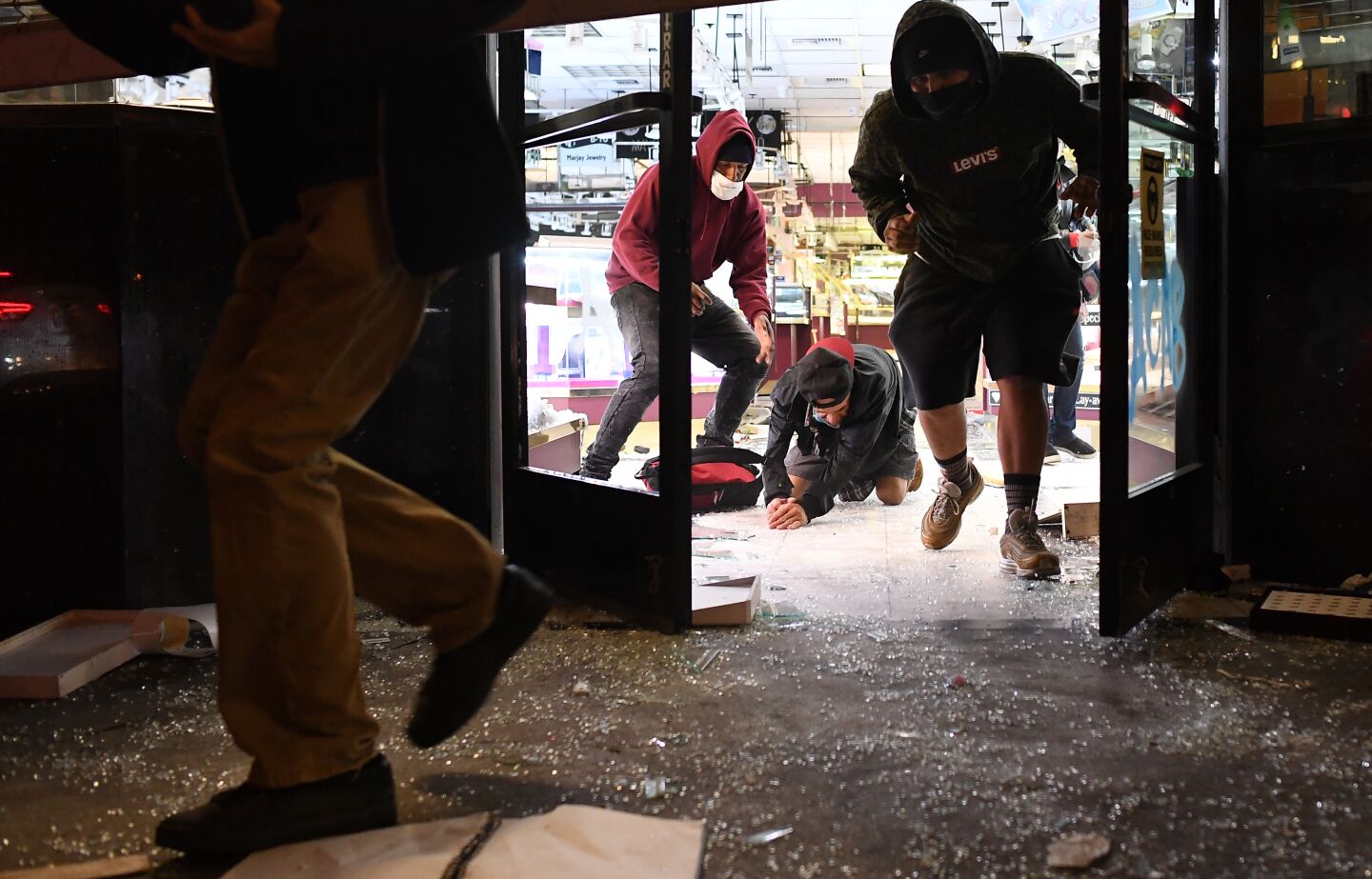 Looters run from a burglarized jewelry store as LAPD officers approach in downtown Los Angeles