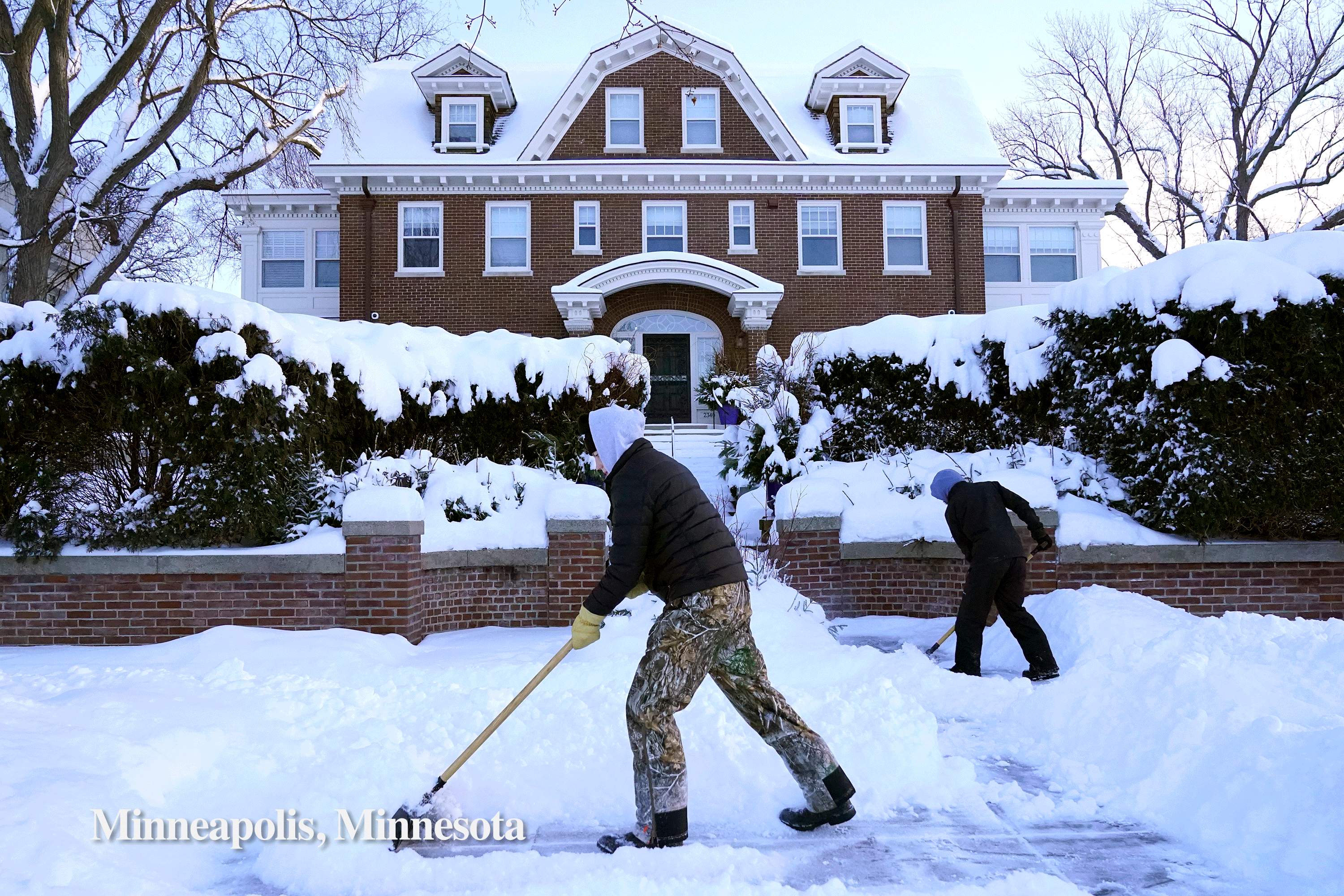 People clear snow from the sidewalk in Minnesota and the Angels Gate Lighthouse in San Pedro