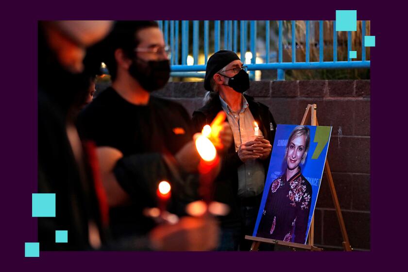 People hold candles around a portrait of a woman at a vigil.