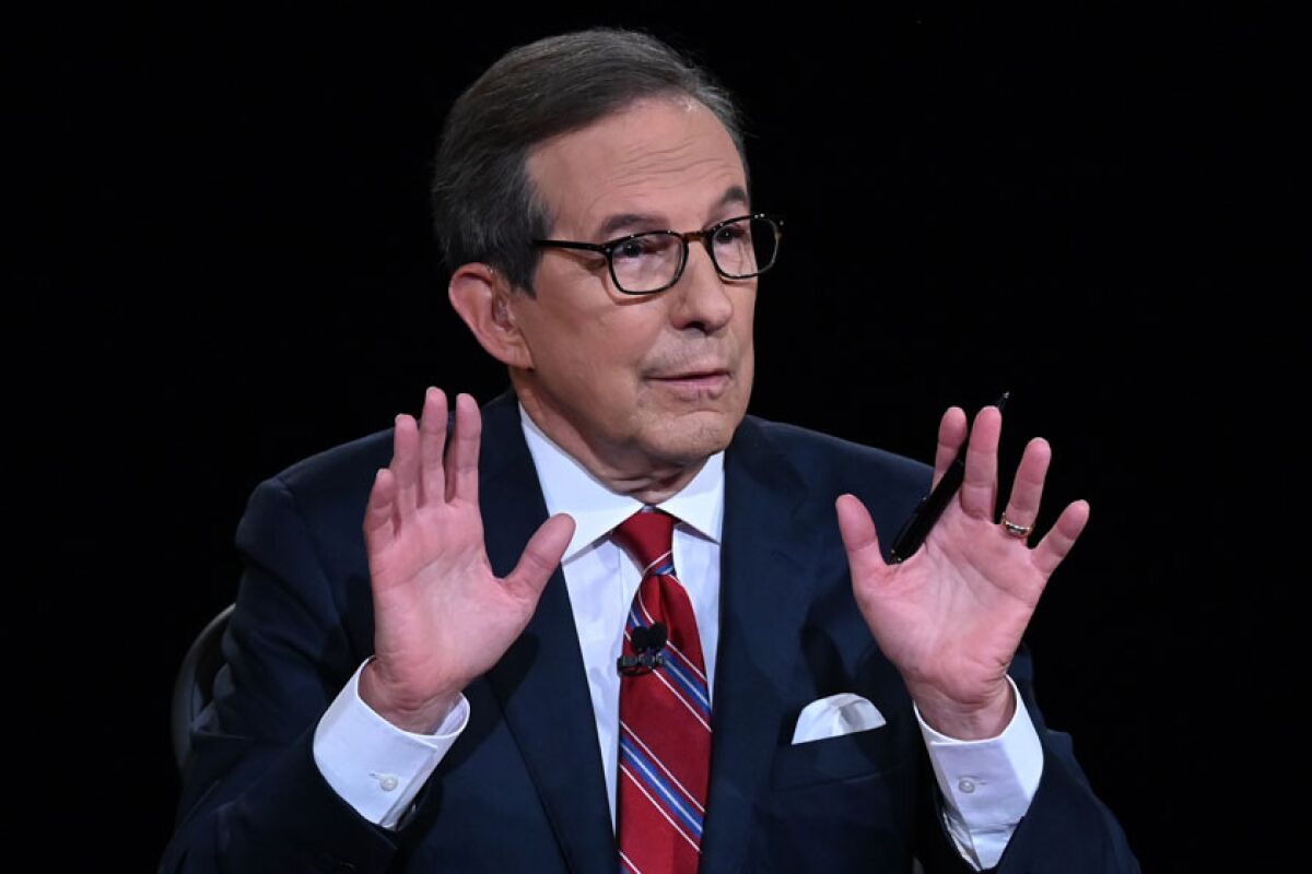 Chris Wallace holds his hands up with a pen in one of them while talking.