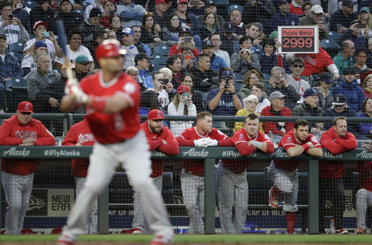A fan holds up a sign of the current number of hits by Los Angeles Angels' Albert Pujols as he comes to the plate in the fourth inning of a baseball game against the Seattle Mariners Friday, May 4, 2018, in Seattle. Pujols hit a single in the fifth inning, the 3,000th hit of his career. (AP Photo/Elaine Thompson)