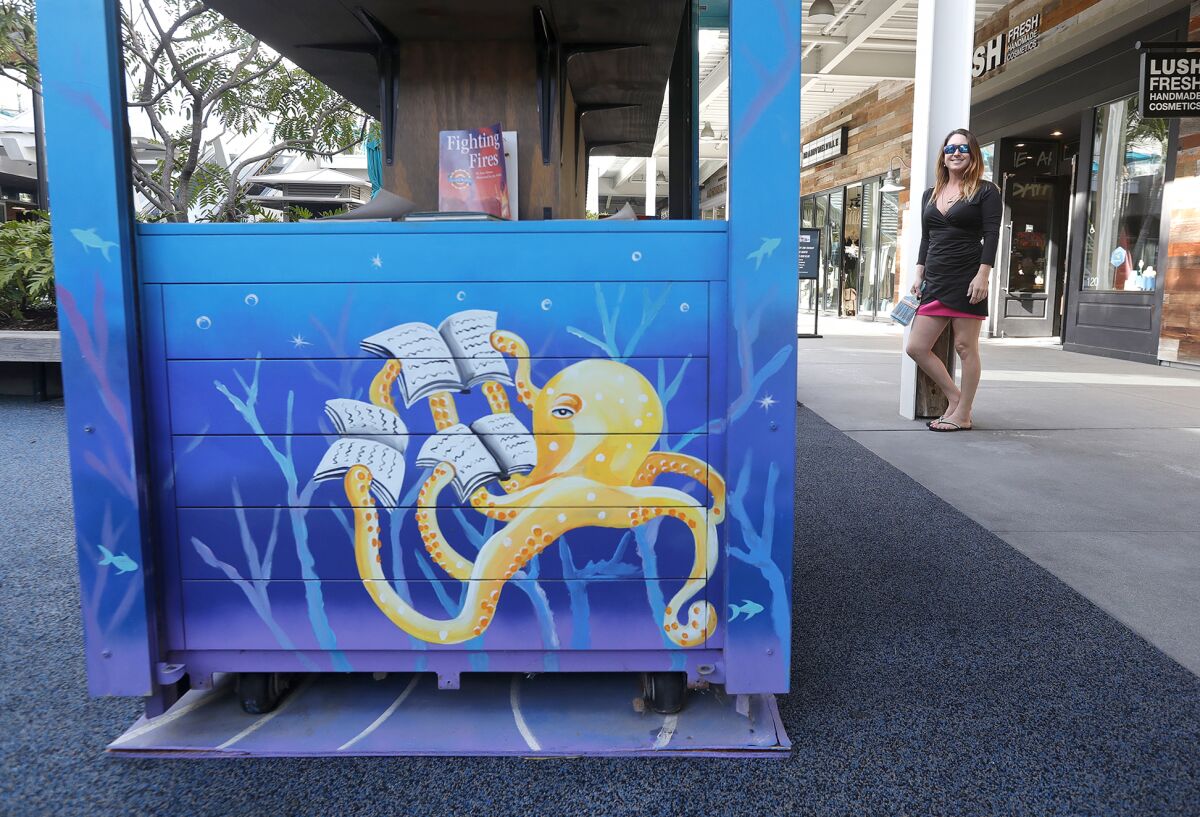 Artist Melissa Murphy stands near one of her signature expansive ocean mural scenes at Pacific City in Huntington Beach.