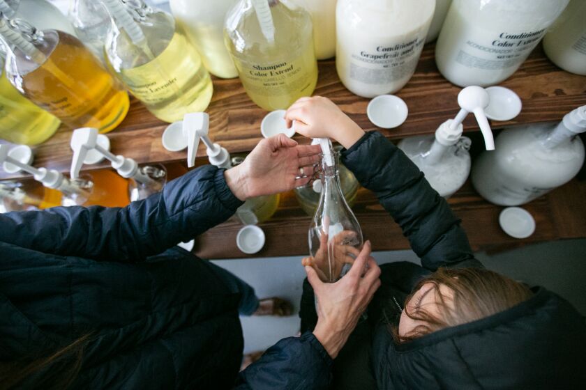 Los Angeles, CA., February 23, 2020 — Kim Staley of Pasadena helps her children (names not given) fill a bootle with hand soap at Sustain.LA, a zero waste store, in Los Angeles on Sunday, February 23, 2020 in Los Angeles, California. (Jason Armond / Los Angeles Times)
