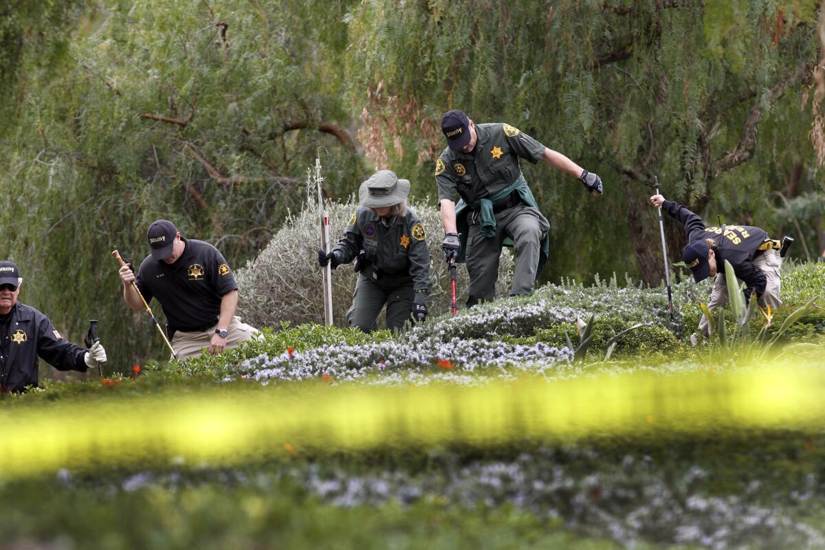 Orange County Sheriff's Search and Rescue team members search near the home where couple were found shot to death.