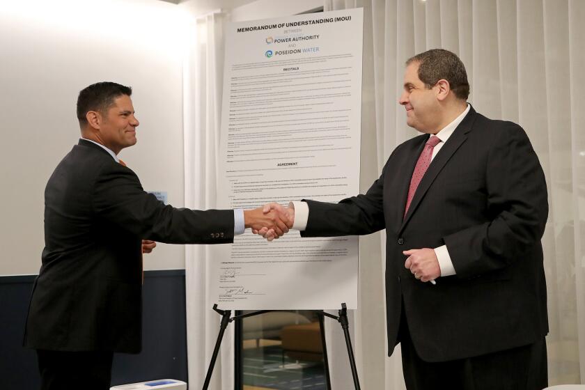 Scott Maloni, left, Poseidon Water Vice President of Project Development, shakes hands with Brian Probolsky, right, Orange County Power Authority CEO, after they both signed their names onto a Memorandum of Understanding (MOU) during a signing ceremony on Tuesday morning in Irvine. They are committing to work together toward the first 100% renewable energy desalination project in the Western hemisphere.