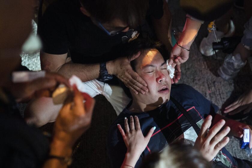 A man is helped by volunteers after getting caught by police pepper spray, near a demonstration in Hong Kong, Monday, Oct. 7, 2019. Tens of thousands of masked protesters marched defiantly in the city center Sunday, but the peaceful rallies quickly degenerated into chaos at several locations as hard-liners again lobbed gasoline bombs, started fires and trashed subway stations and China-linked banks and shops. (AP Photo/Felipe Dana)