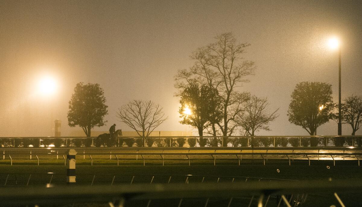 Rain falls as a horse makes its way around the track at Keeneland during Breeders' Cup workouts on Oct. 28, 2015, in Lexington, Ky.