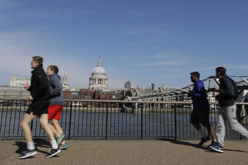 FILE - In this file photo dated Sunday, March 22, 2020, people run to keep fit along the south bank of the River Thames in London. European Union regulators have said Tuesday Aug, 4, 2020, they're opening an in-depth investigation into U.S. tech giant Google's plan to buy fitness tracking device maker Fitbit. (AP Photo/Kirsty Wigglesworth, FILE)