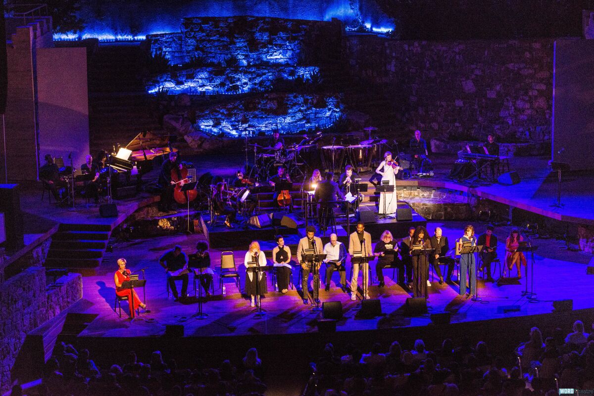 Performers line up on stage at the Ford, cast in blue and purple lighting. 