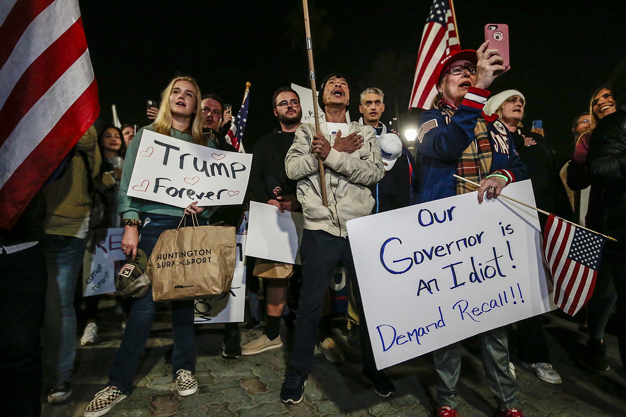 Protesters carry signs reading "Trump Forever" and "Our governor is an idiot."