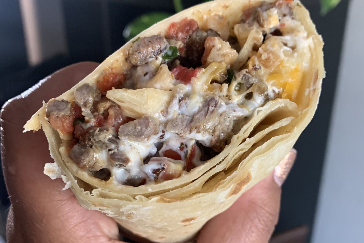 cross section of a burrito with fries, steak, sour cream, cheese and pico de gallo
